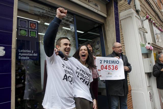 Varias personas celebran, a la puerta de una Administración de loterías del Estado, un premio de su sorteo de Navidad