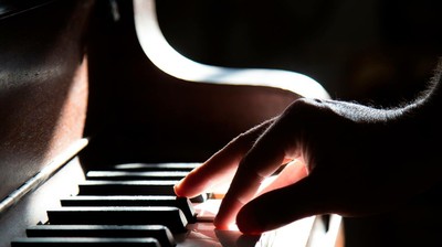Cartel del curso de creatividad musical: una mano posada en un teclado de piano