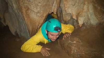 Un joven afiliado repta por una grieta del terreno para salvar una dificultad durante el recorrido