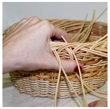 Imagen de la mano de una mujer realizando un trabajo de cestería
