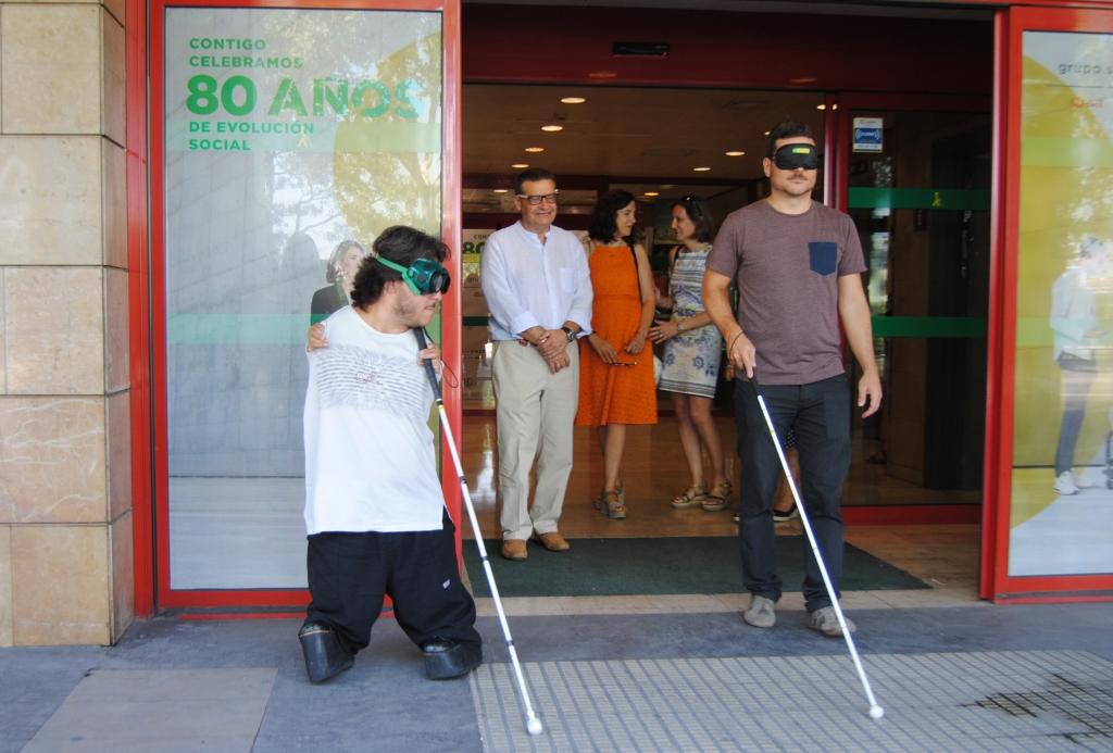 Gay (a la izquierda) e Ignacio Escartín dan un paseo por el entorno de la Delegación con los ojos tapados y valiéndose tan sólo del bastón como guía