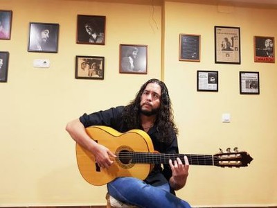 Sergio Molido posa con su guitarra junto a fotografías de Paco de Lucía, Camarón de la Isla, etc.