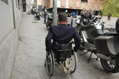 Persona en silla de ruedas por la acera