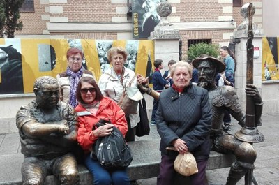 Usuarias del servicio de teleasistencia posan en Alcalá ante una escultura callejera de Quijote y Sancho