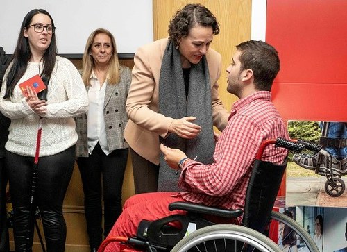 La ministra hace entrega de su 'pasaporte' a uno de los alumnos en silla de ruedas