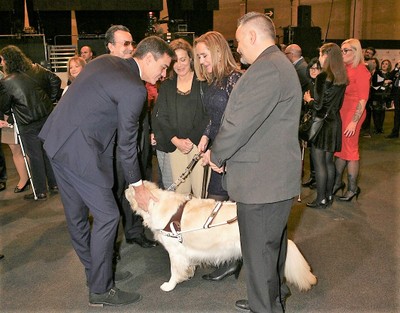 Sánchez saluda a los representantes de la Fundación ONCE del Perro Guía (FOPG) y acaricia a uno de estos canes
