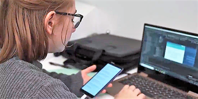 Foto de www.smartcity.es: una joven trabaja con el teclado braille de su ordenador y al tiempo con un terminal móvil
