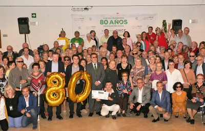 Foto de detalle de los asistentes con los representantes de la ONCE, posando con el símbolo del 80 aniversario