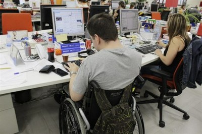 Un trabajador en silla de ruedas, junto a otros compañeros, en la Redacción de la agencia Servimedia