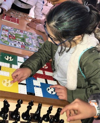 Una niña comprueba cómo manejarse con un parchís adaptado para las personas ciegas