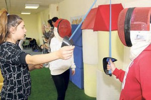 Dos jóvenes tiradores de esgrima con discapacidad visual reciben instrucciones de una monitora en el club de Pontevedra