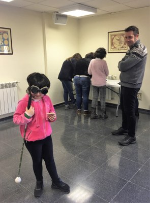 Una niña afiliada con su bastón durante una de las prácticas abordadas en la jornada, junto a su padre, que la observa
