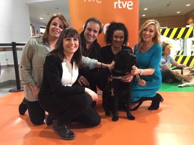 Varios de los presentadores participantes en la experiencia posan con uno de los perros guía de la ONCE