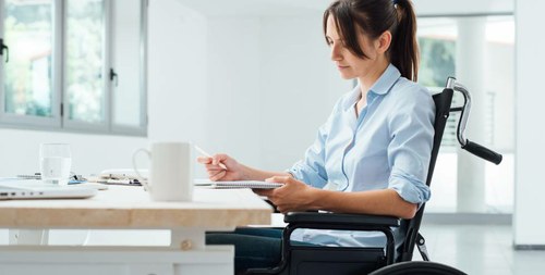 Mujer joven en silla de ruedas, trabajando