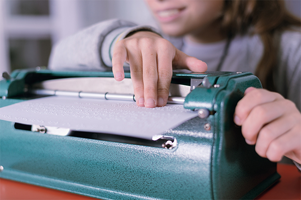 Niña ciega manejando una máquina Perkins