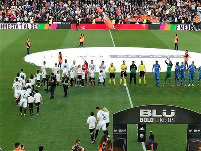 Niños afiliados a la ONCE saltan al césped acompañando al equipo titular del Valencia (equipado de blanco)