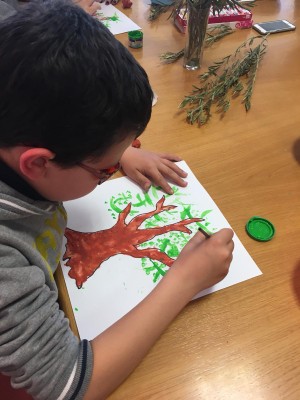 Otro de los niños colorea su dibujo de un olivo
