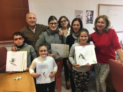 Varios pequeños afiliados posan, con sus respectivas fichas sobre el aceite, junto a los instructores del taller