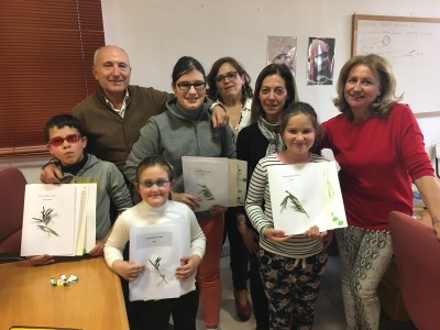 Varios pequeños afiliados posan, con sus respectivas fichas sobre el aceite, junto a los instructores del taller
