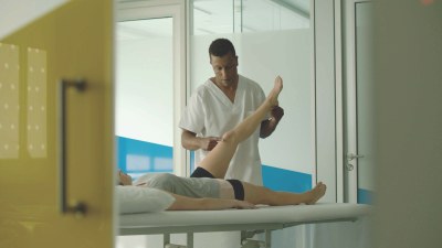 Un técnico de Ilunion Fisioterapia y Salud atiende a una paciente