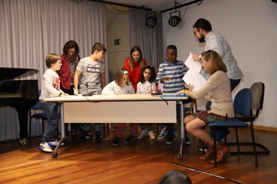 Niños afiliados del CRE de Madrid leen poemas sobre el escenario del salón de actos de la Territorial