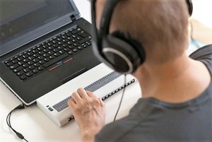 Un joven ciego trabaja con su ordenador y una línea braille