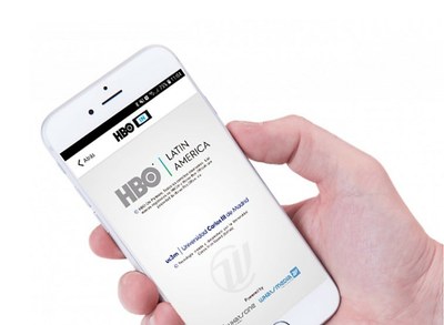 Una mano sostiene un teléfono móvil cuya pantalla muestra la aplicación de HBO IN