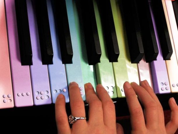 Manos tocando un teclado de piano en braille