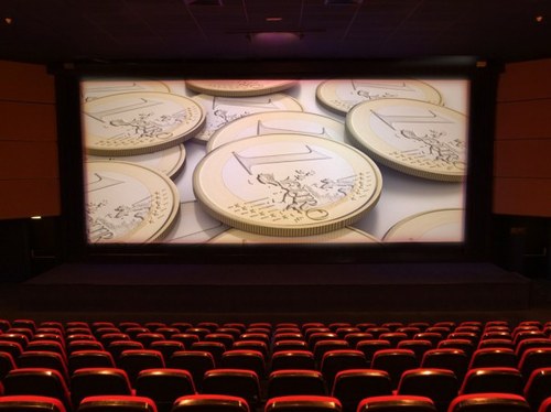 Sala de cine con imagen de monedas en la pantalla