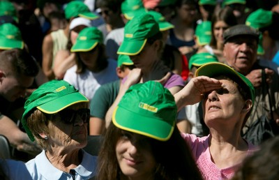 Los asistentes al acto se protegen del sol con gorras verdes de la ONCE