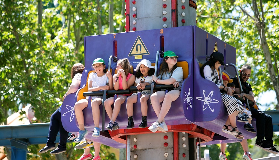 Un grupo de niñas con gorras de la ONCE disfrutan en una de las atracciones del Parque