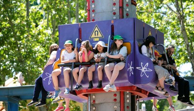 Un grupo de niñas con gorras de la ONCE disfrutan en una de las atracciones del Parque