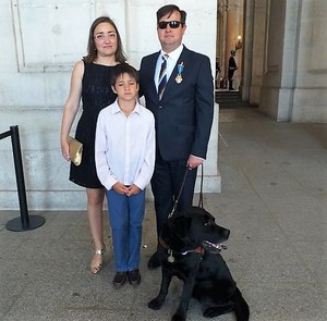 Javier González, junto a su mujer, su hija y su perra guía, a las puertas del Palacio Real