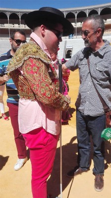 Un afiliado con chaquetilla de luces, bastón blanco y sombrero cordobés en mitad del ruedo
