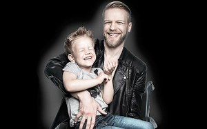 Imagen promocional del certamen: un padre en silla de ruedas con su hijo en brazos