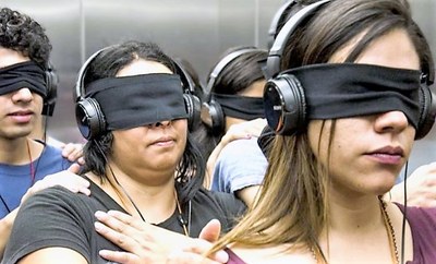  Un grupo de personas con los ojos vendados y cascos en los oídos simbolizando la sordoceguera
