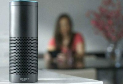 Un terminal de Alexa, en primer plano, con una mujer difuminada al fondo