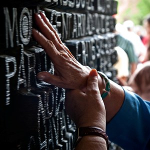 Unas manos reconocen al tacto una inscripción en relieve sobre una superficie pétrea en la Sagrada Familia de Barcelona