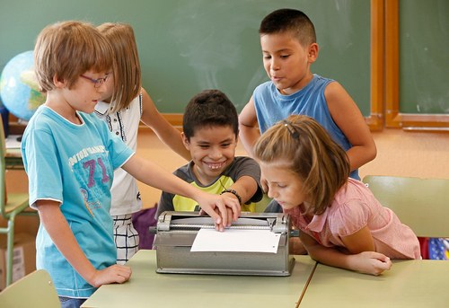 Un niño afiliado escribe, rodeado de sus compañeros de clase, en una máquina Perkins
