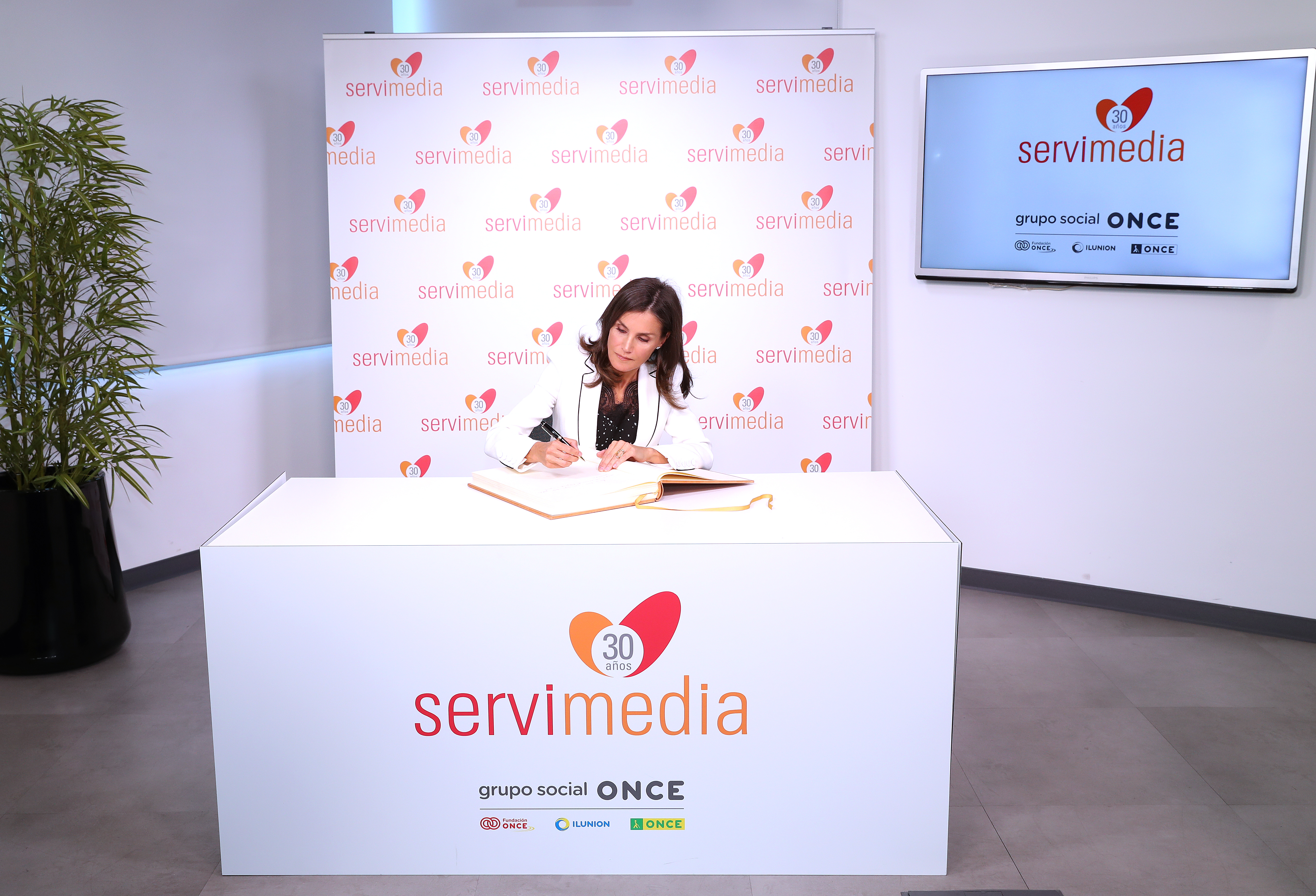 La reina firma en el Libro de Honor de Servimedia