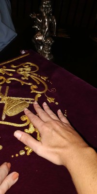 Tocando un detalle de un bordado en oro
