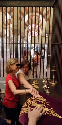 Una voluntaria ayuda a una afiliada a reconocer un bordado en oro al tacto