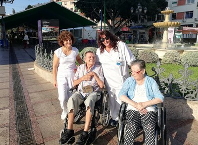 Dos usuarios del servicio, en sus sillas de ruedas, acompañados por dos acompañantes del servicio de atención municipal