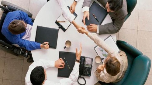 Mesa de trabajadores en una oficina, uno de ellos en silla de ruedas