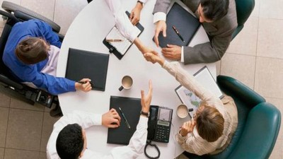 Mesa de trabajadores en una oficina, uno de ellos en silla de ruedas