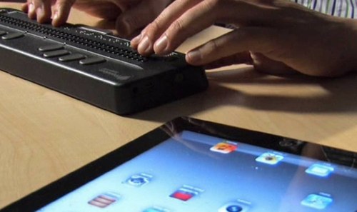 Línea braille junto a una tablet
