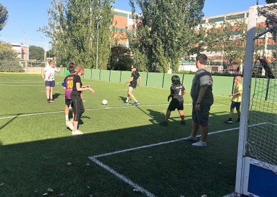 Chicos y chicas ensayando el tiro a portería en una práctica de fútbol
