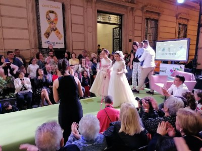 Dos niñas afiliadas (una de ellas con su bastón), ataviadas con trajes de primera comunión, desfilan sobre la pasarela