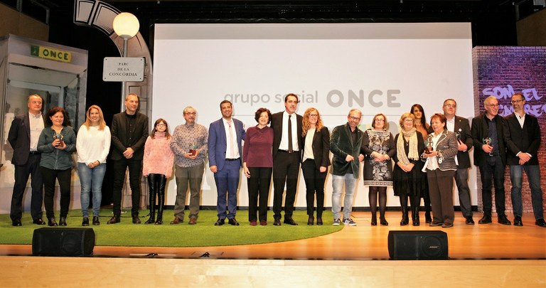 Foto de familia de premiados y autoridades, sobre el escenario, al finalizar el acto