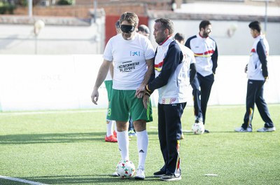 Gaitán, miembro del equipo de fútbol de ciegos, asesora a un trabajador de la Caixa sobre cómo orientarse en el campo sin visión